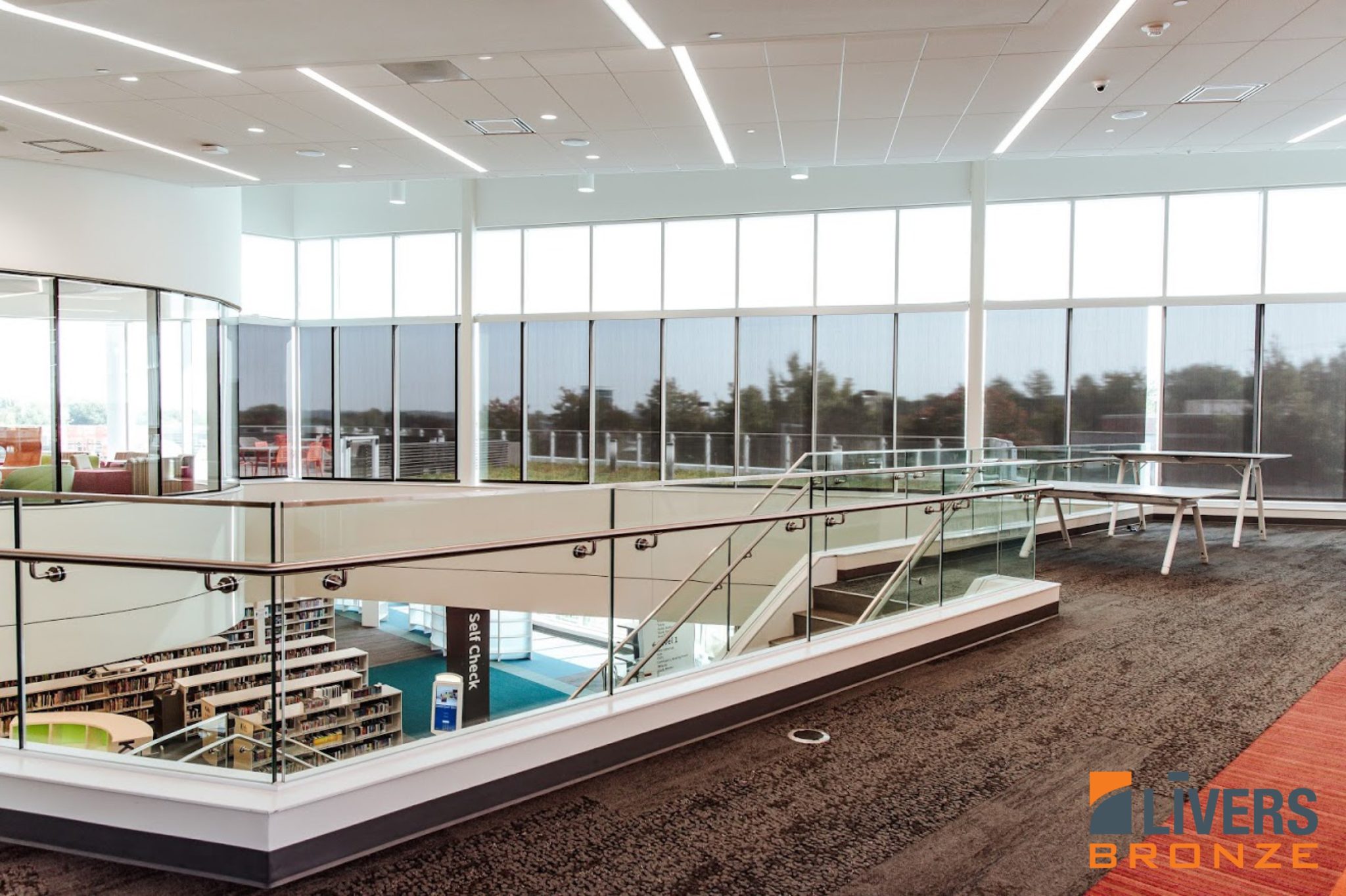 Livers Bronze Struct-U-Rail Commercial Glass Railing system installed at the lobby stair and interior balcony at the Monticello Public Library, Shawnee, Kansas, and is Made in the USA.